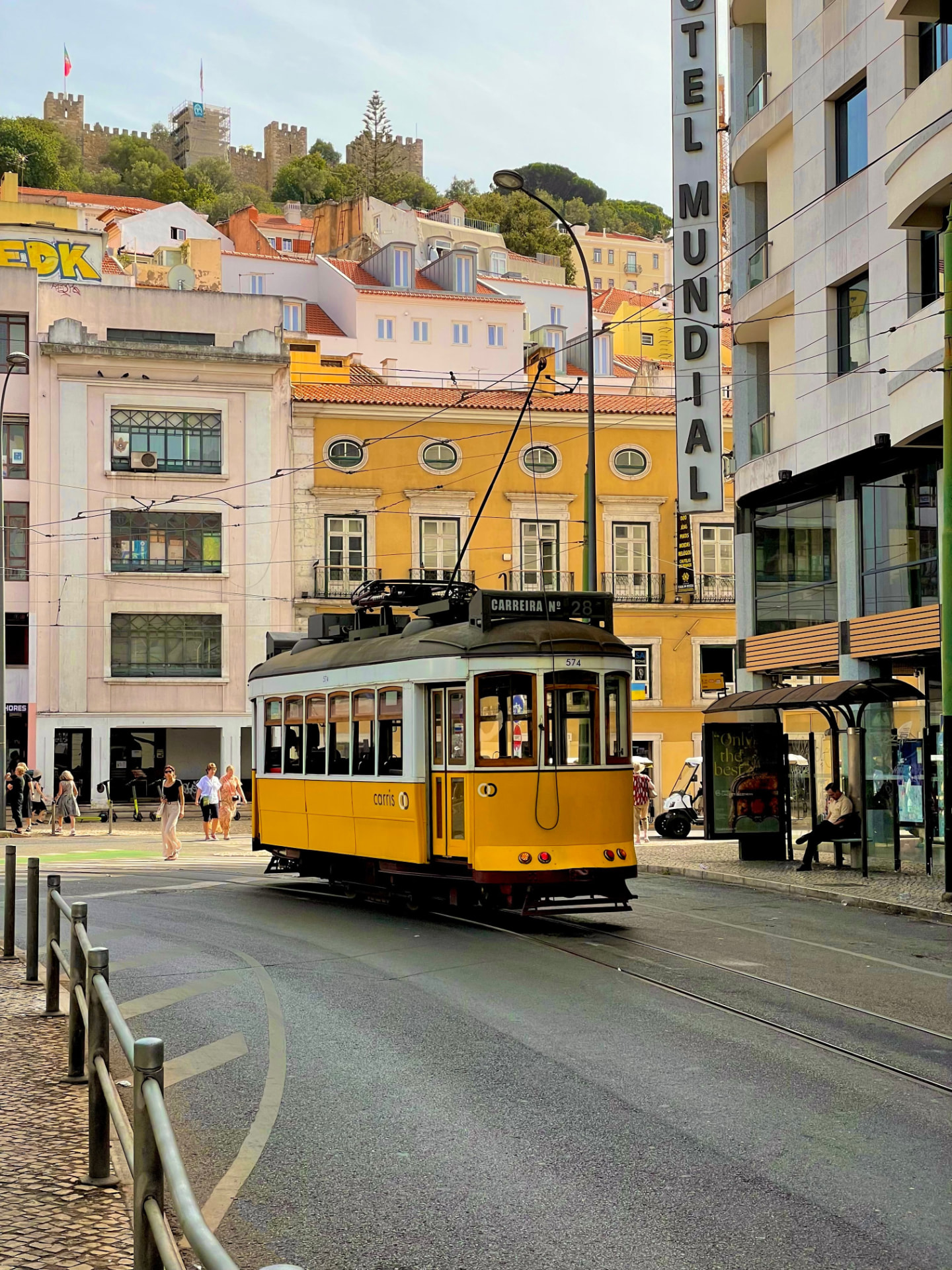 Tramway jaune 28 dans une rue de Lisbonne, château Saint-Georges en arrière-plan