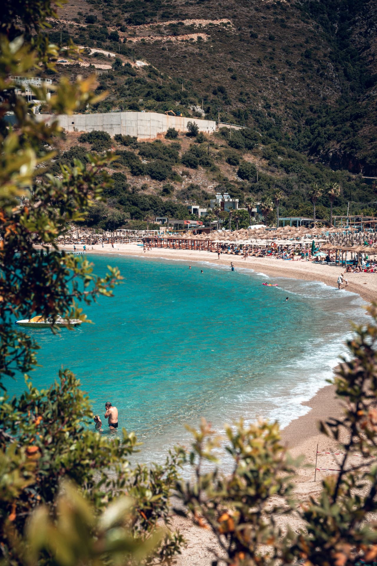 Crique turquoise et plage de la Riviera albanaise vue à travers la végétation